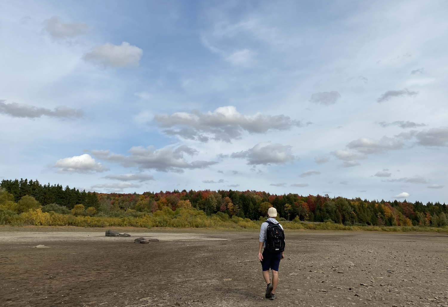 A person walking through an open landscape under a cloudy sky